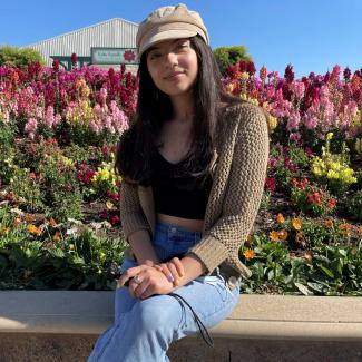 a casual image of peer mentor priscilla in front of a field of flowers